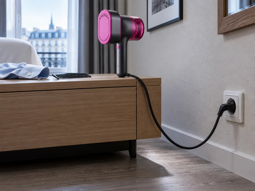 A low horizontal photograph in a real European hotel room showing the exact compact magenta-pink and